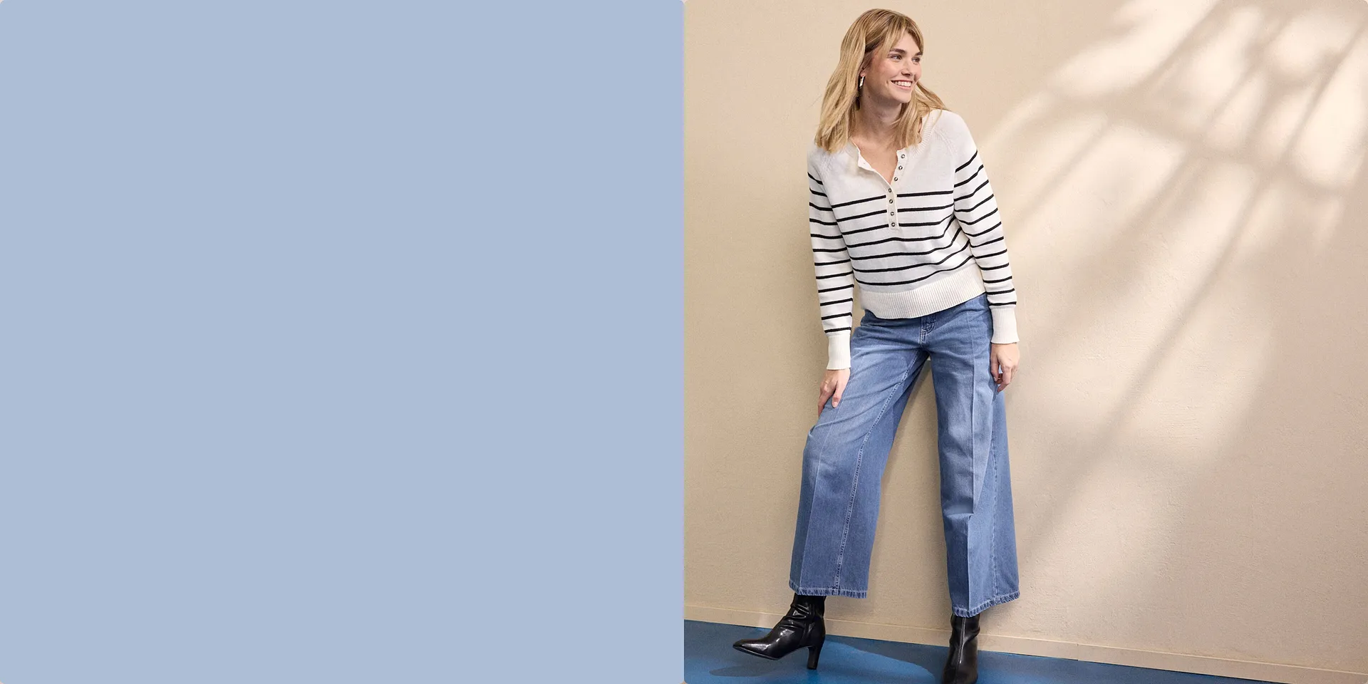 Gestreifter weißer Pullover mit Reißverschluss, kombiniert mit weiten Jeans und schwarzen Stiefeln.