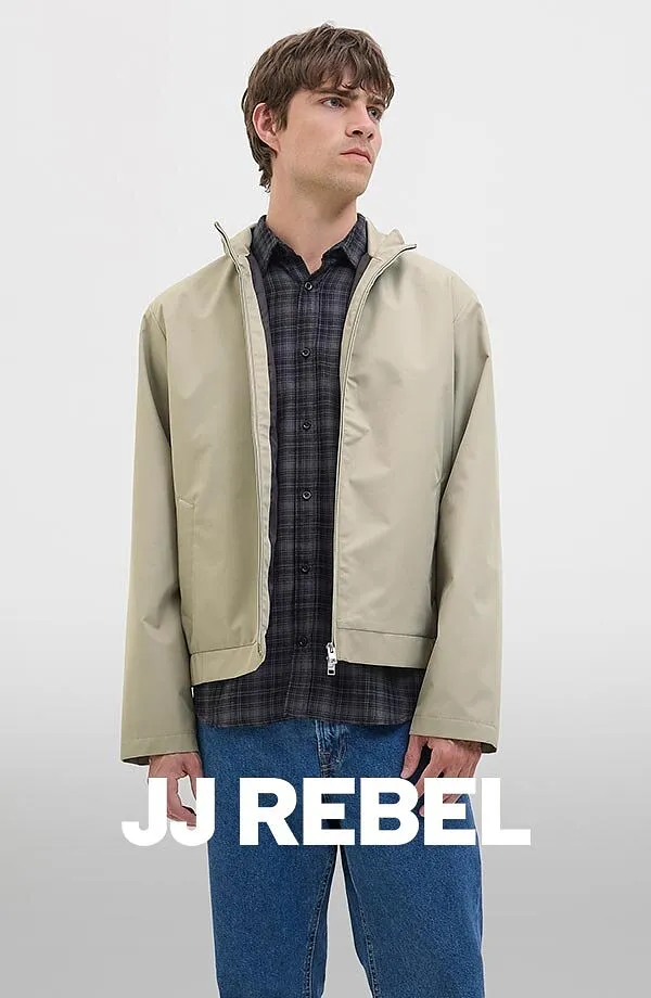 Chemise à carreaux sous une veste beige, associée à un jean bleu.