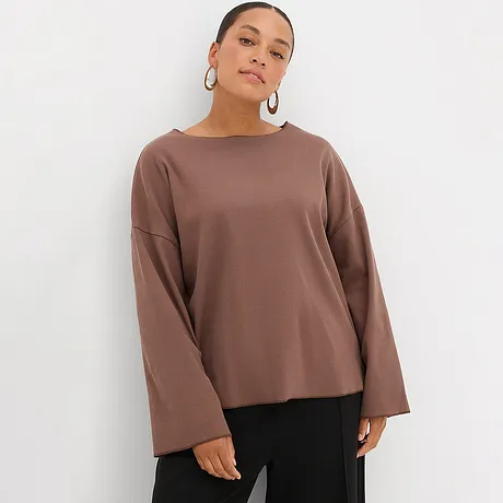 T-shirt à manches longues marron avec manches amples, associé à un pantalon noir.