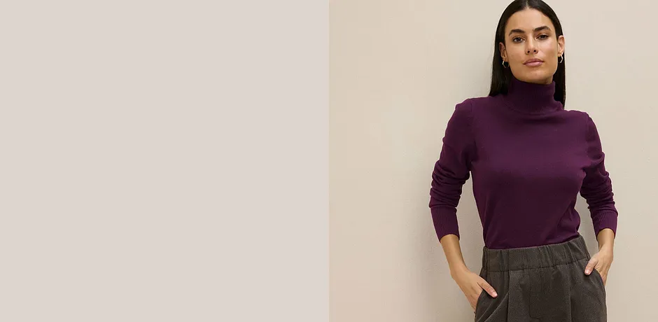 Lila Rollkragenpullover kombiniert mit grauer Hose.