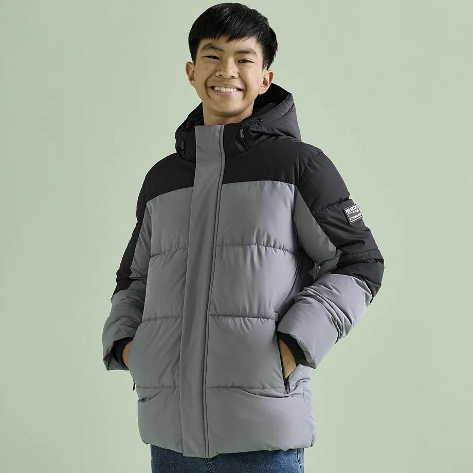 Junge trägt eine zweifarbige Winterjacke in Grau und Schwarz.