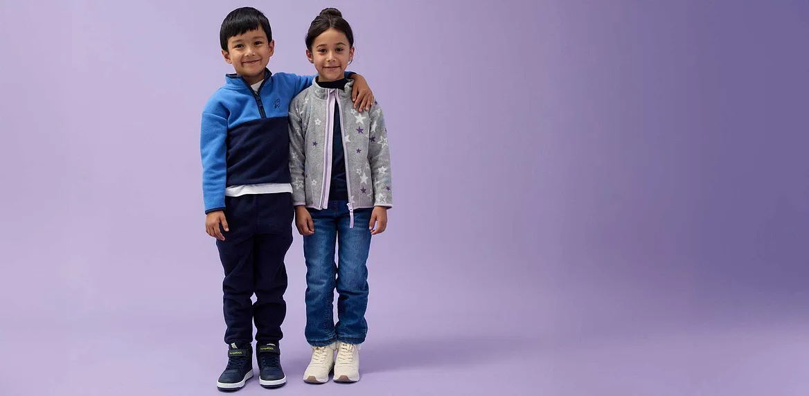 Kinder in Jeans und Jacken: blaue Jacke für ihn, graue Jacke für sie.
