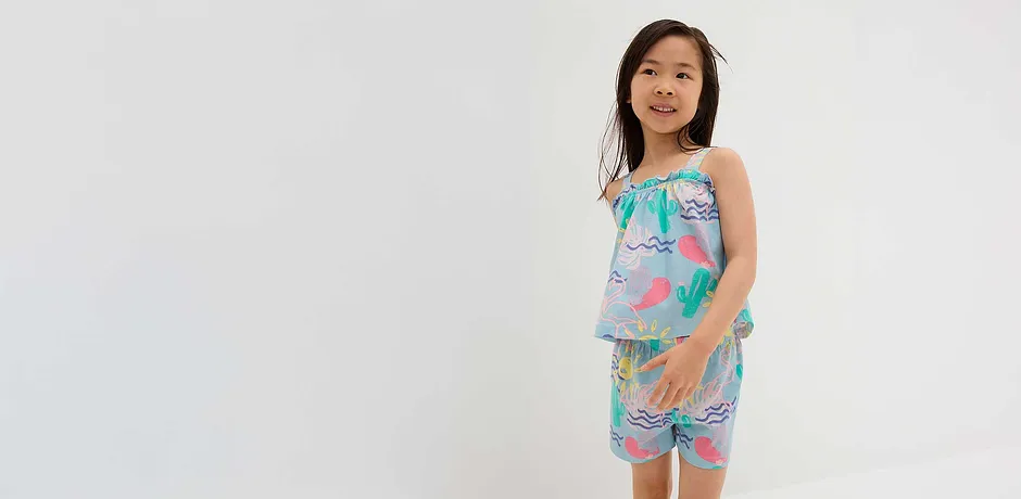 Tenue d'été composée d'un top et d'un short dans des teintes pastel, avec des motifs de flamants roses et cactus.