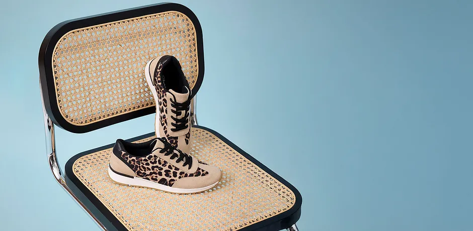Sneakers léopard stylées sur une chaise tressée.