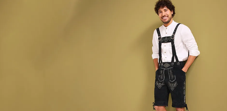 Weißes Hemd, schwarze Lederhosen mit Trägern und dekorativen Stickereien.