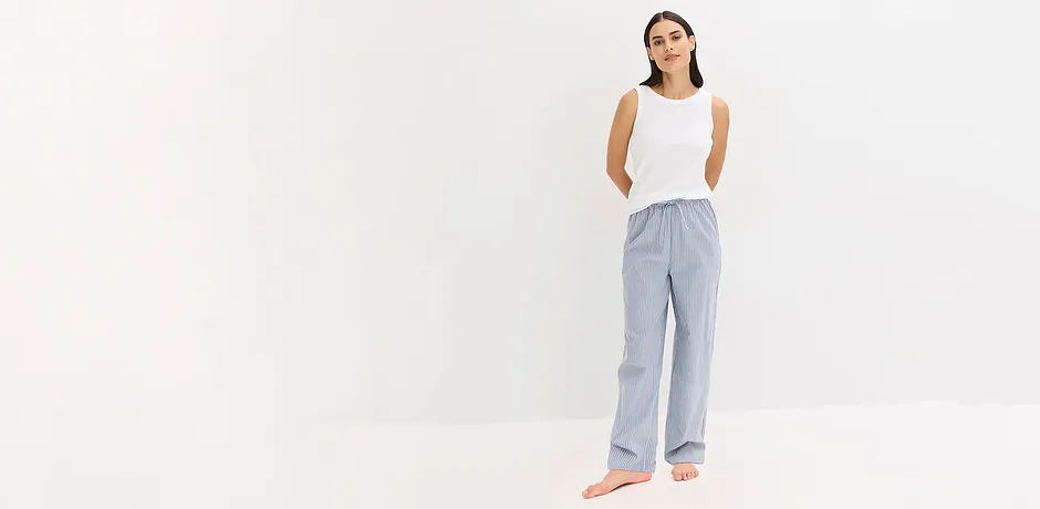 Lässiger Pyjama-Look: Weißes ärmelloses Top kombiniert mit gestreifter, luftiger Hose für entspannte Eleganz.