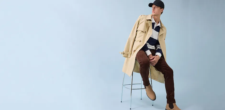 Stilvoller Trenchcoat, braune Hose und schwarze Kappe - moderner Look für den Alltag.