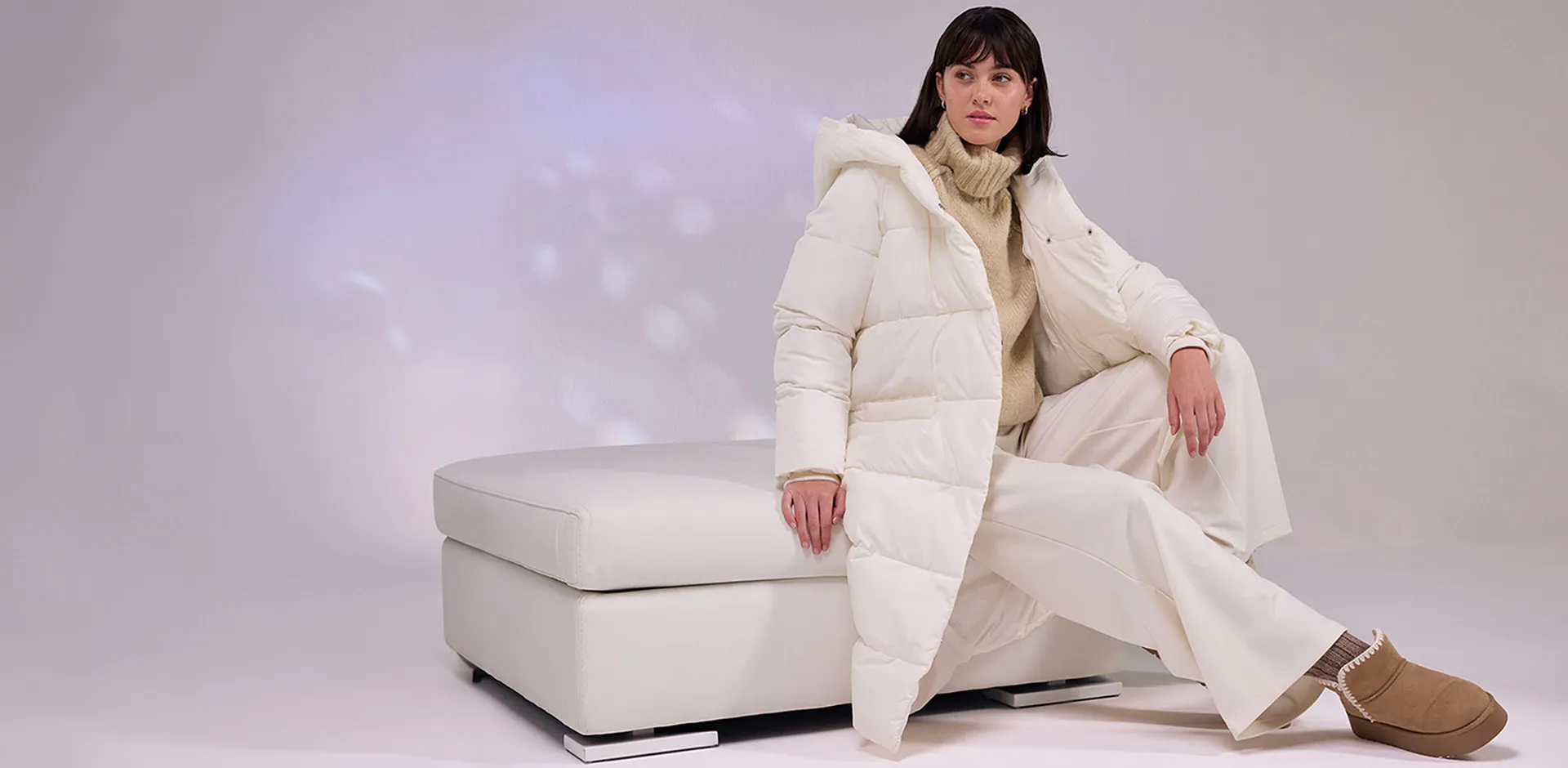 Cremefarbener Daunenmantel, weiße Hose und flauschige Boots.