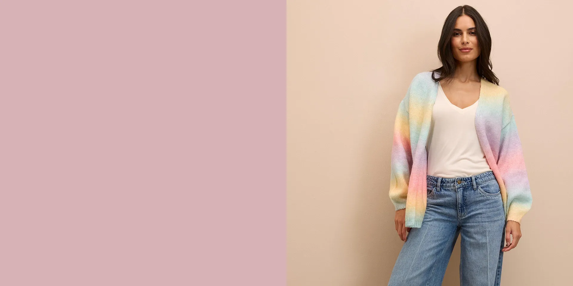 Pastellfarbene Strickjacke über weißem Top, kombiniert mit weiten Jeans für einen lässigen Look.