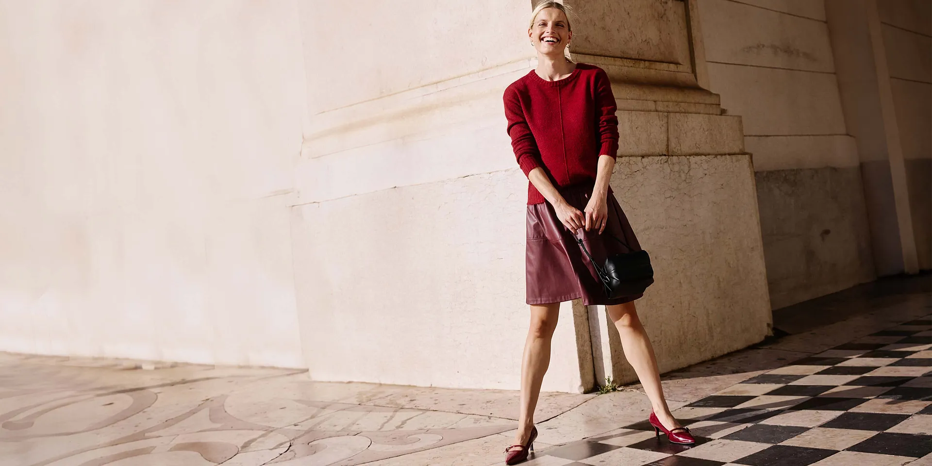 Roter Pullover und kurzer roter Rock kombiniert mit schwarze Tasche.