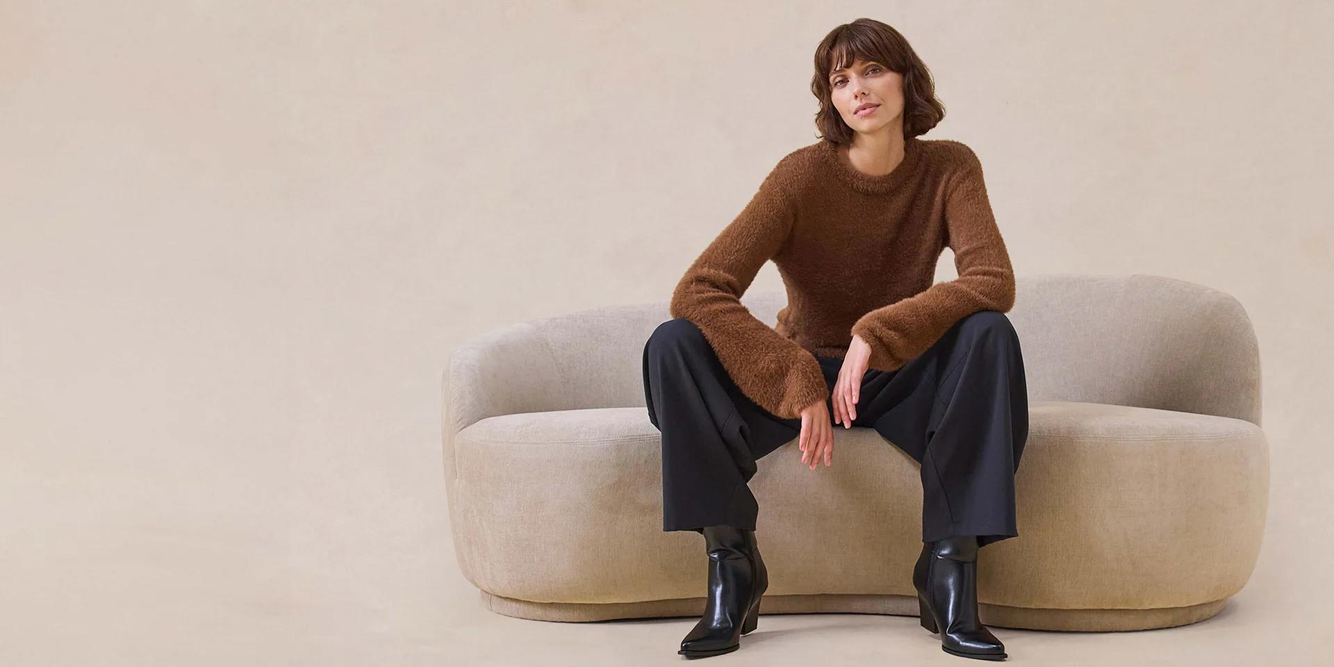 Pull marron élégant, pantalon large et bottes noires.