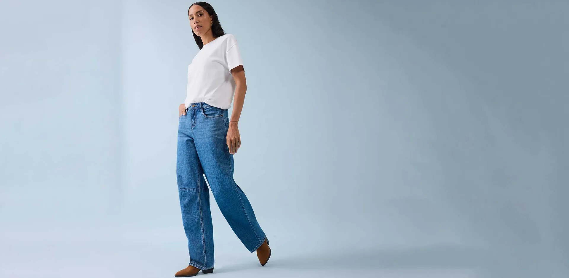 Klassisches weißes T-Shirt kombiniert mit weiten Jeans und braunen Schuhen.