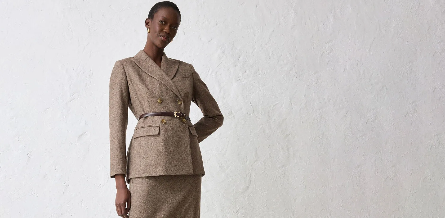 Blazer beige avec ceinture, associé à une jupe assortie.