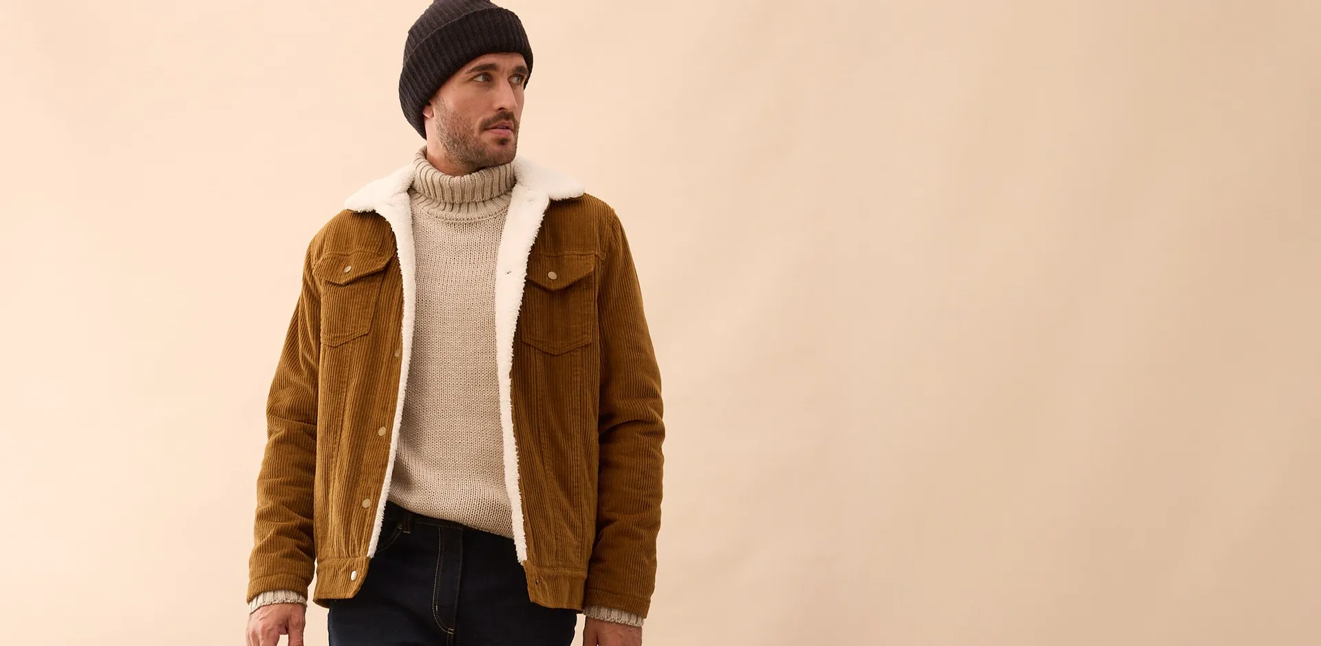 Un ensemble &eacute;l&eacute;gant compos&eacute; d'une veste en daim marron, d'un pull &agrave; col roul&eacute; couleur cr&egrave;me et d'un bonnet noir.