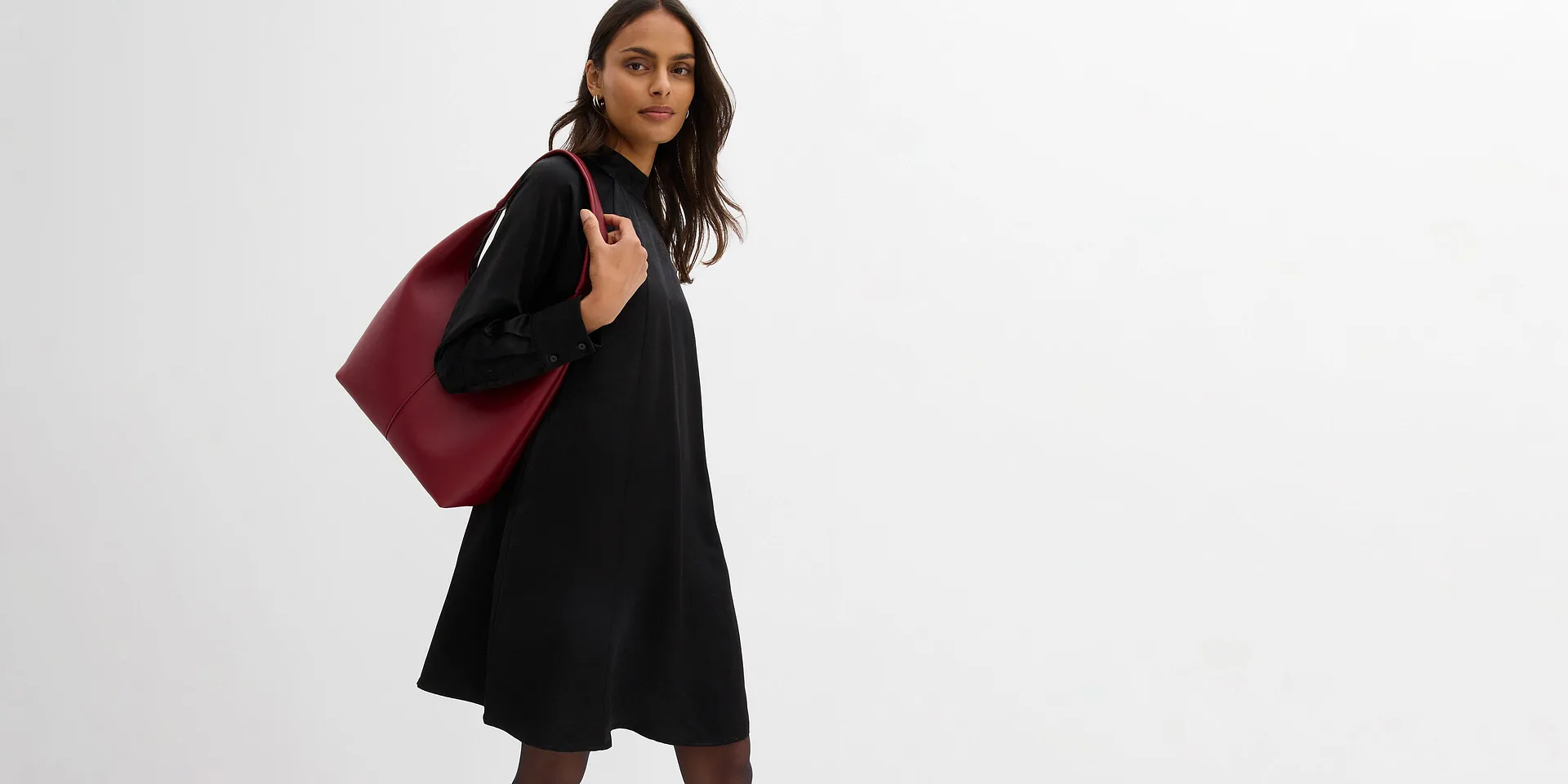 Schwarzes Kleid mit hohem Kragen und wei&szlig;em Kragenschmuck. Kurze L&auml;nge und lang&auml;rmelig.