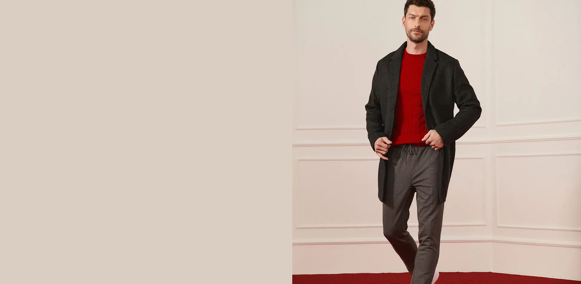 Manteau en laine foncé, pull rouge et pantalon gris pour un look élégant.