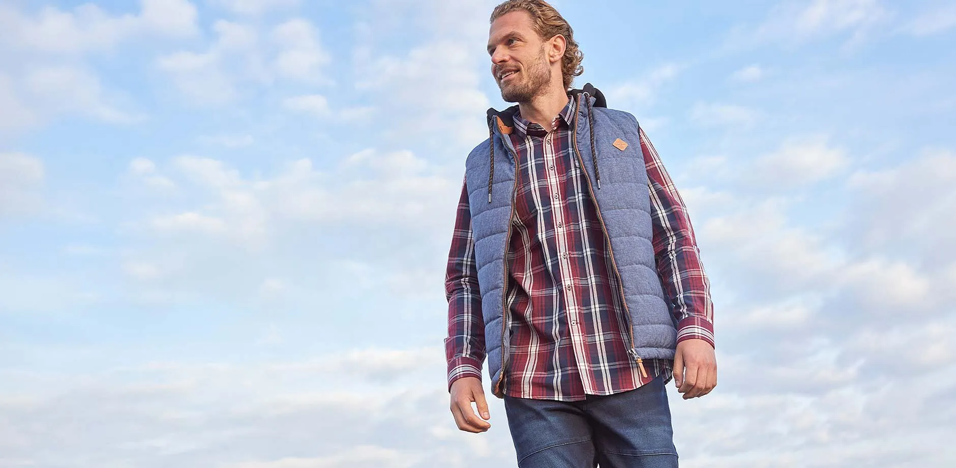 Chemise &agrave; carreaux, jean bleu et veste sans manches grise.