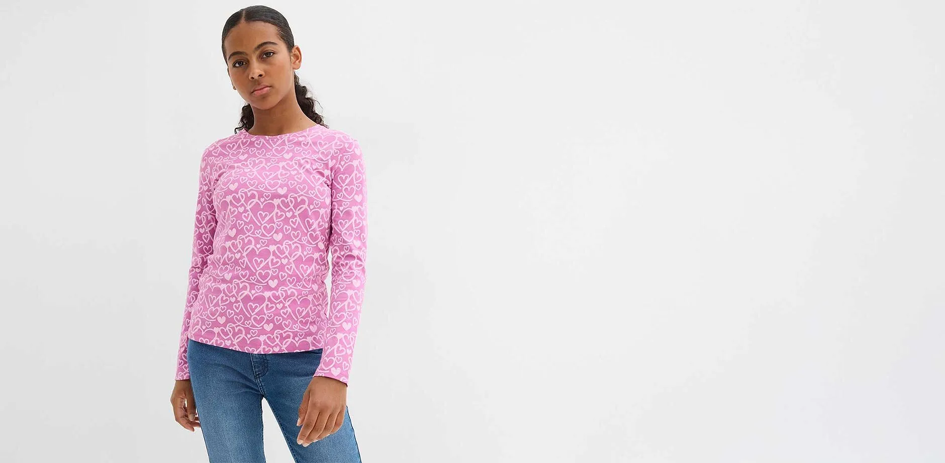 Rosa Pullover mit wei&szlig;em Leopardenmuster, blaue Jeans. L&auml;ssiger Look f&uuml;r den Alltag.