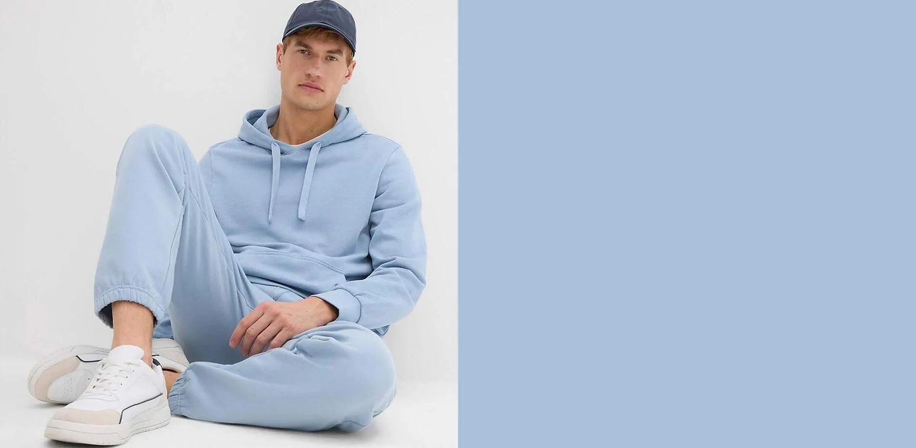 Kapuzenpullover und Jogginghose. Dazu wei&szlig;e Sneaker und dunkle Baseballkappe.