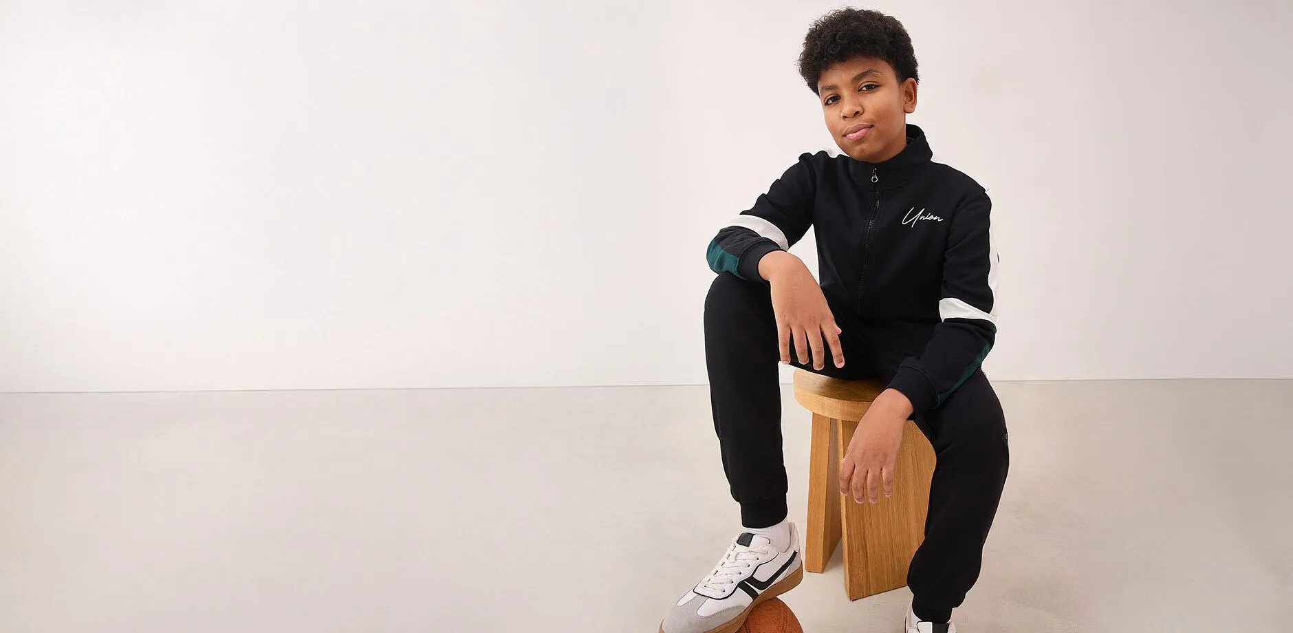 Blaue Jacke mit wei&szlig;em Logo, l&auml;ssige Jeans und Sneaker.