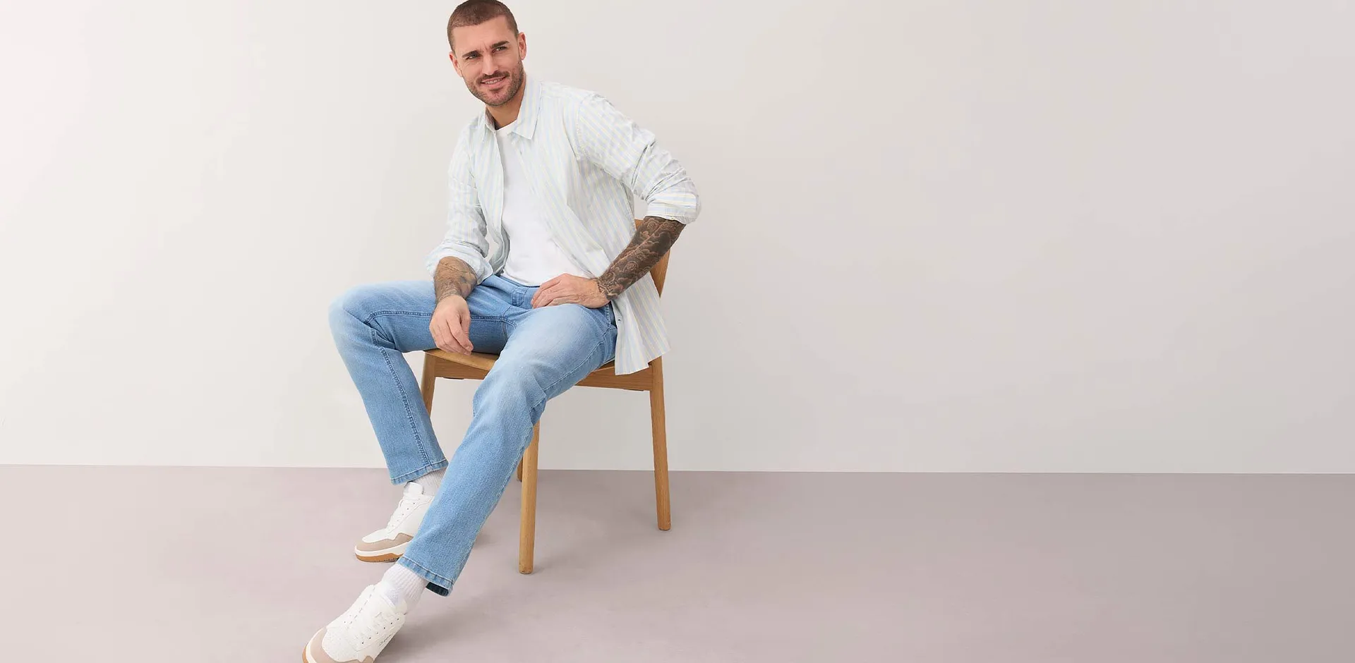 Chemise blanche ray&eacute;e, jean bleu clair et sneakers blanches.