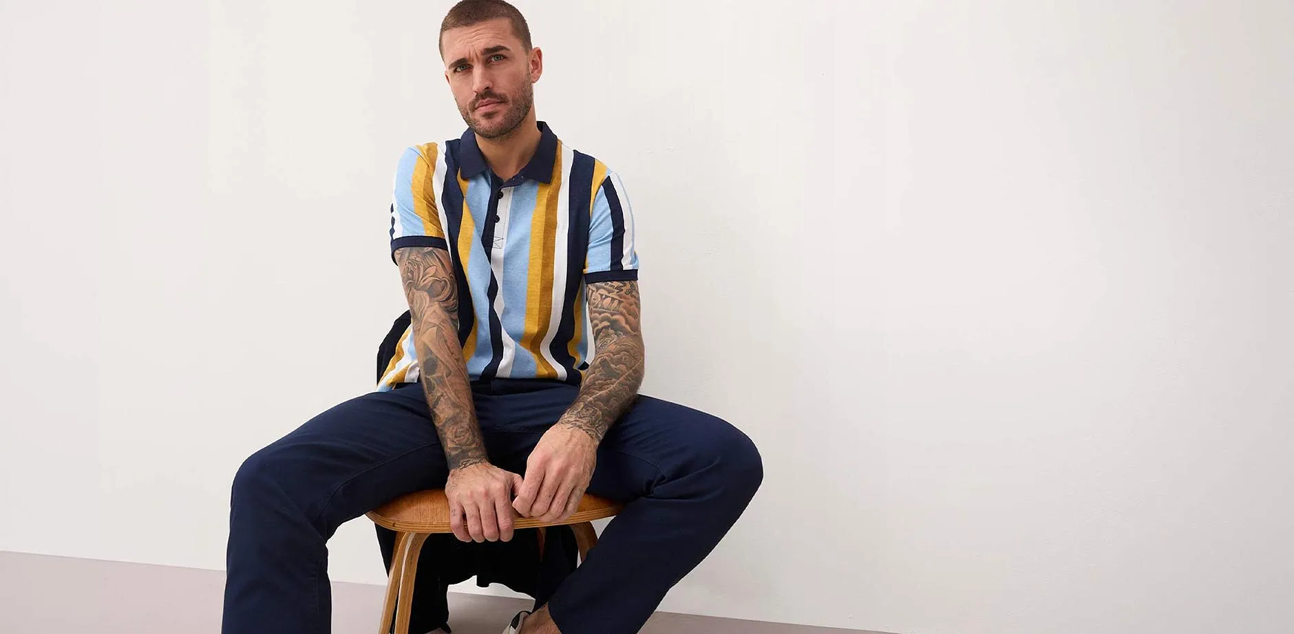 Gestreiftes Poloshirt in Blau, Gelb und Wei&szlig;. Dunkelblaue Hose. 