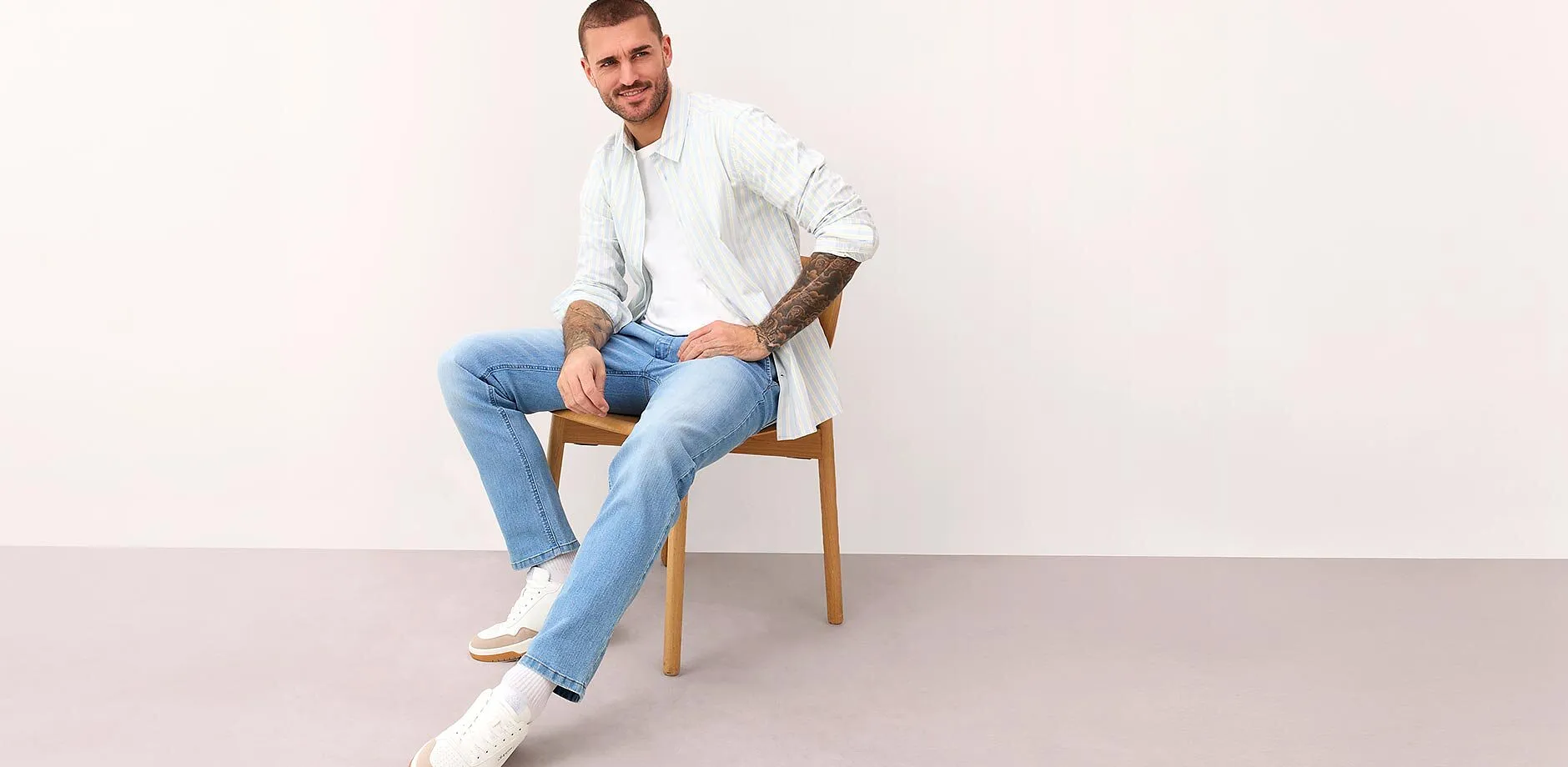 Wei&szlig;es, gestreiftes Hemd, hellblaue Jeans und wei&szlig;e Sneaker.