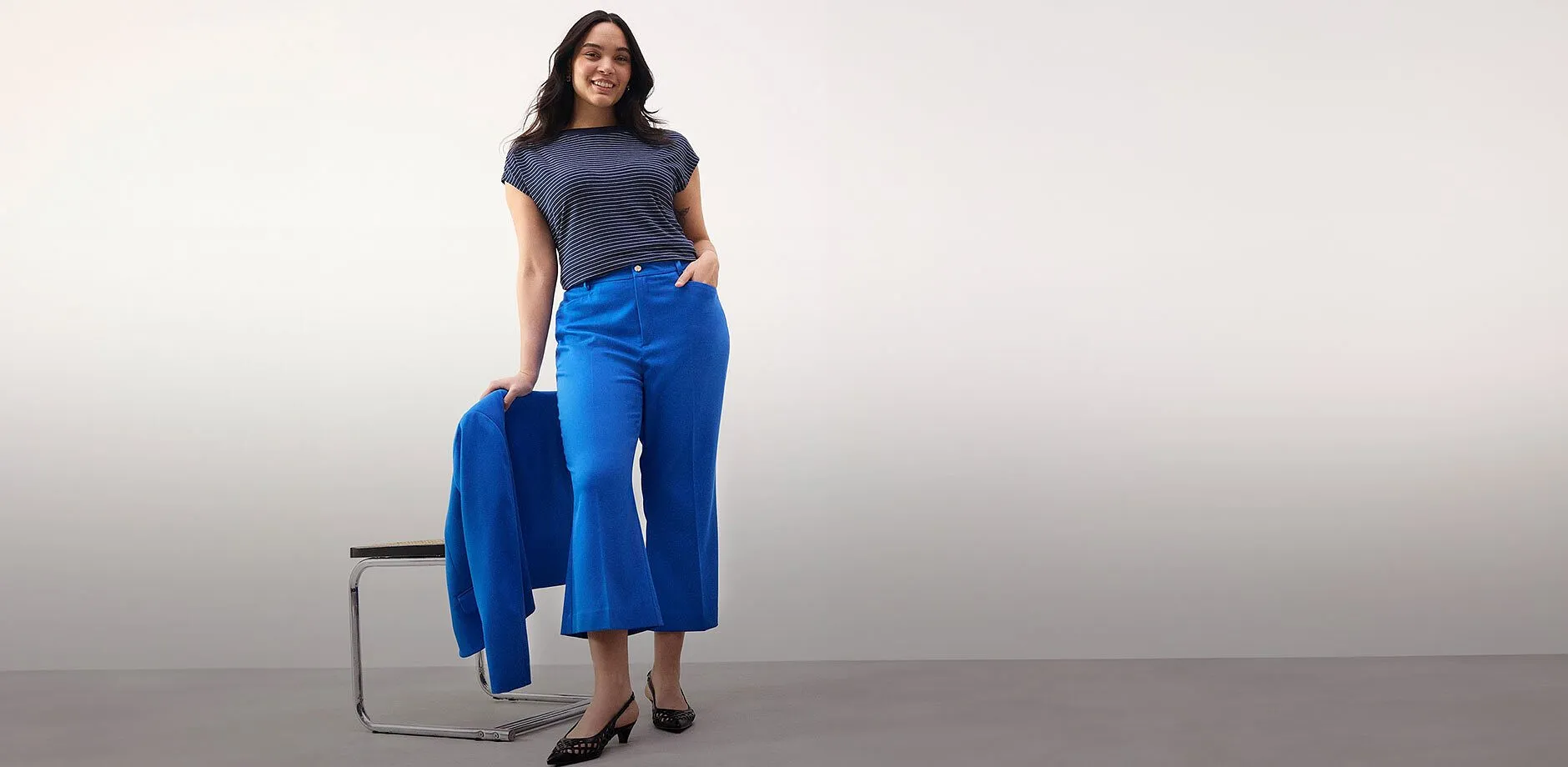 Une femme rayonnante dans un ensemble pantalon bleu marine.