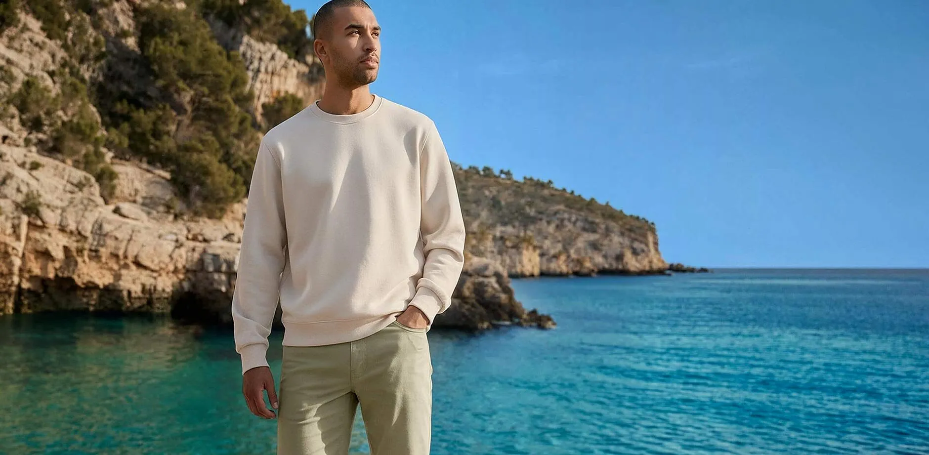 Cremefarbenes Sweatshirt und helle Hose am Meer.