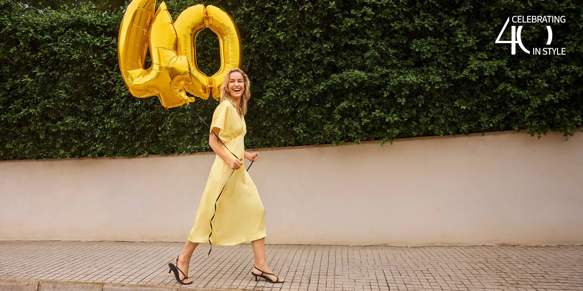 Une robe jaune estivale &agrave; manches courtes, compl&eacute;t&eacute;e d'une paire de sandales noires &eacute;l&eacute;gantes.