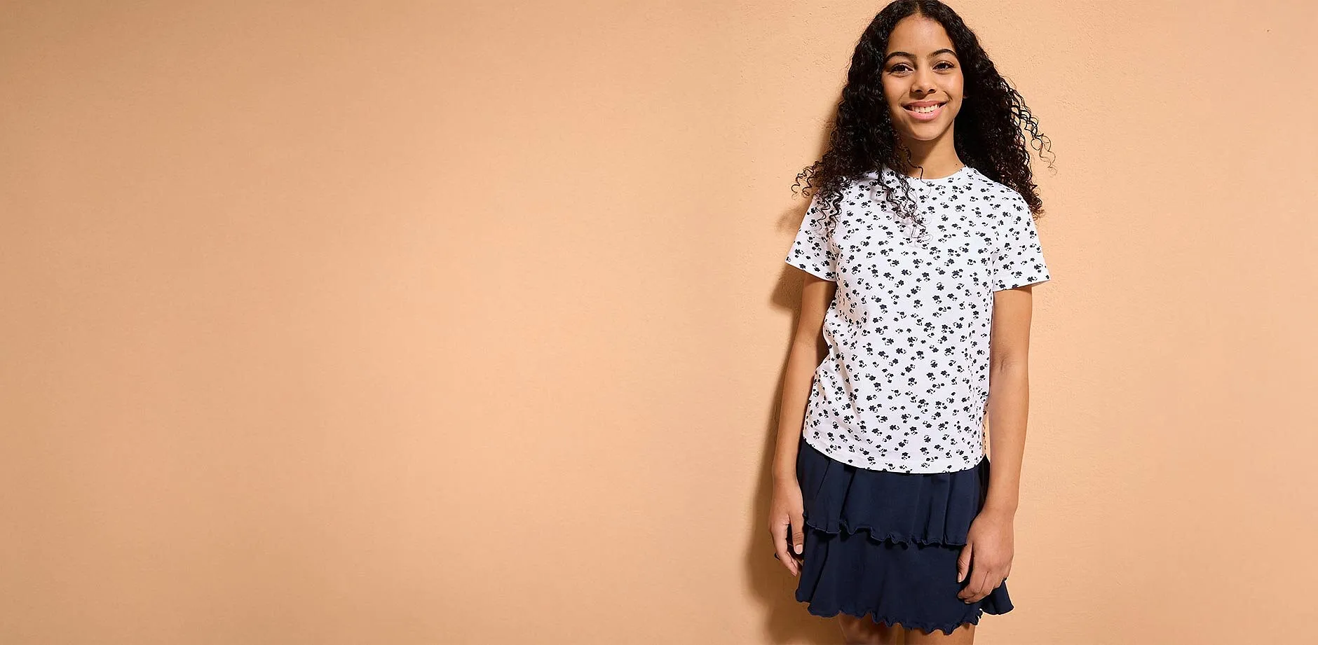 Ein M&auml;dchen tr&auml;gt ein wei&szlig;es T-Shirt mit Muster.