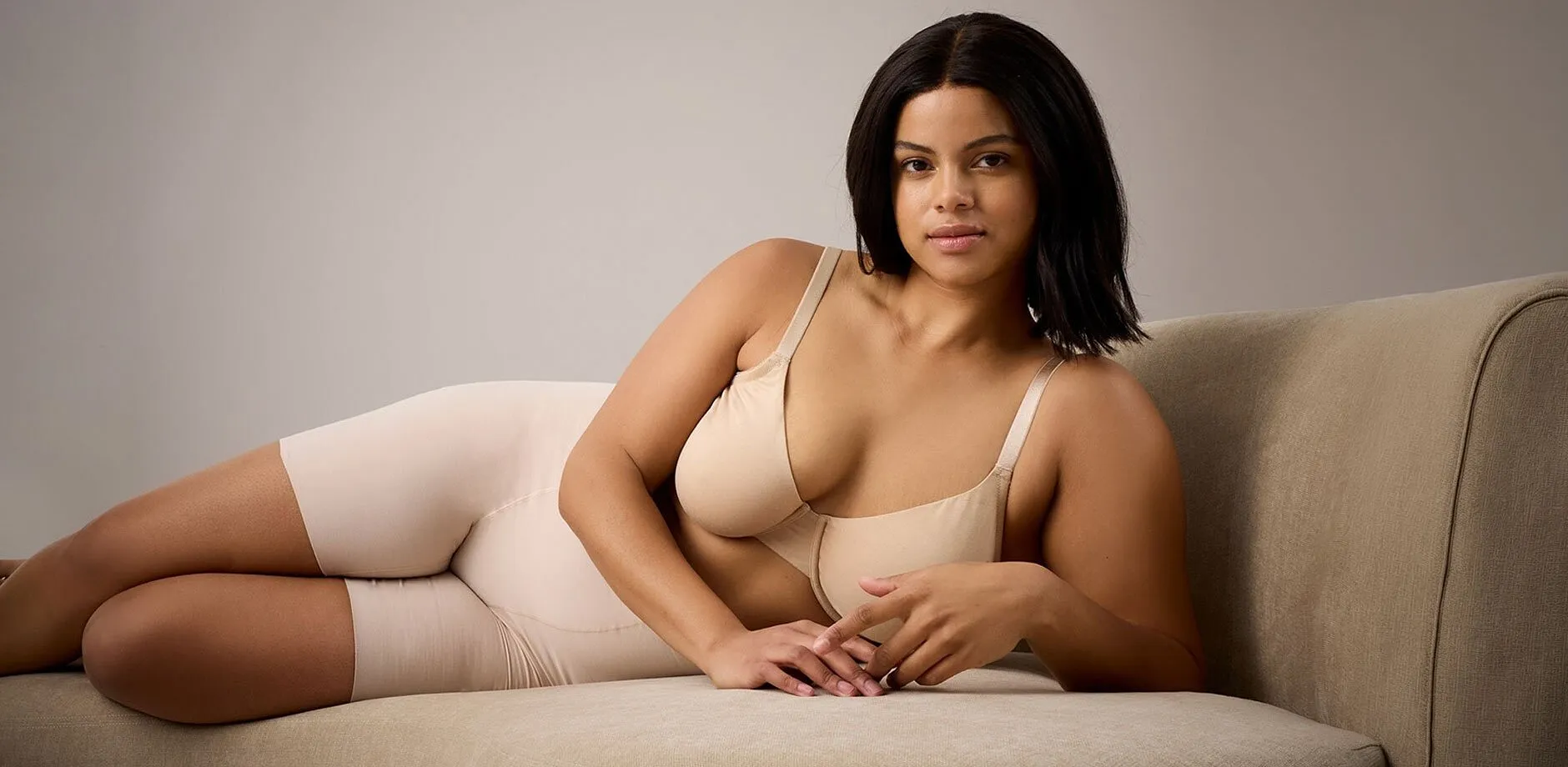 Sous-v&ecirc;tements de couleur beige pour souligner vos atouts et votre beaut&eacute; naturelle. Notre mod&egrave;le pose semi-allong&eacute; sur un canap&eacute; de couleur cr&egrave;me.