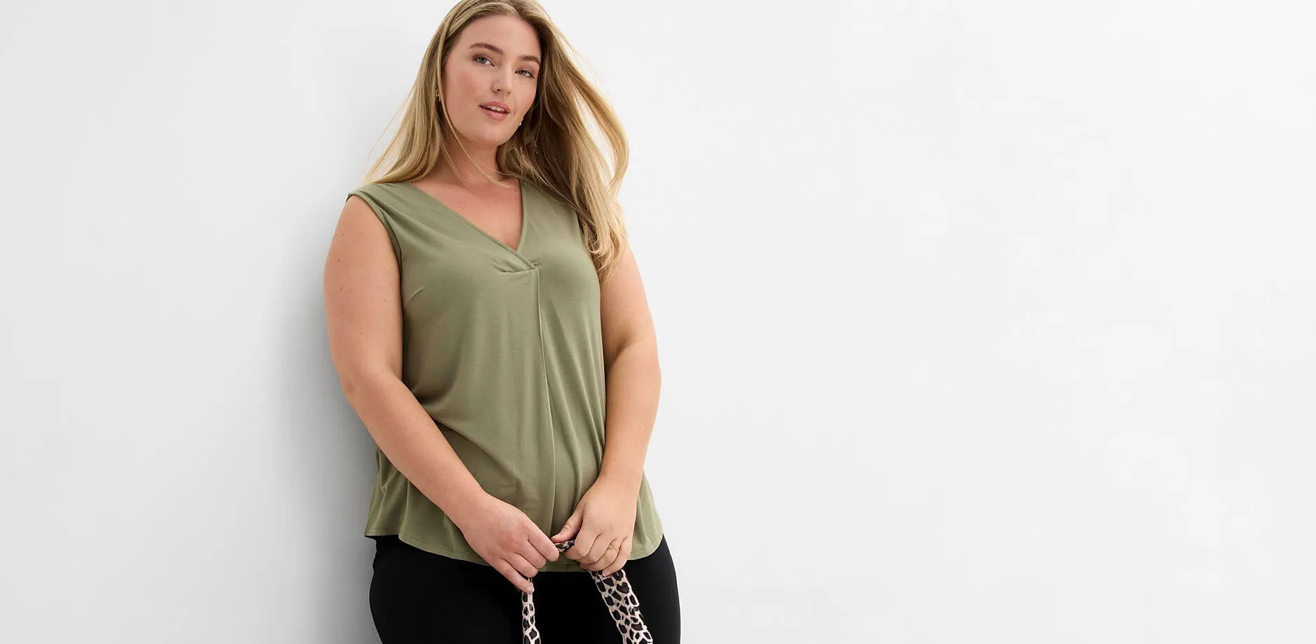 Top ample sans manches vert olive et pantalon noir.