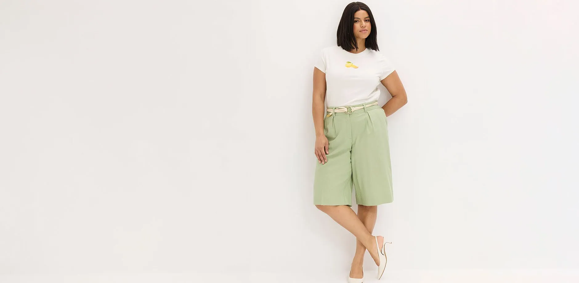 T-shirt blanc, bermuda vert menthe et sandales beige.