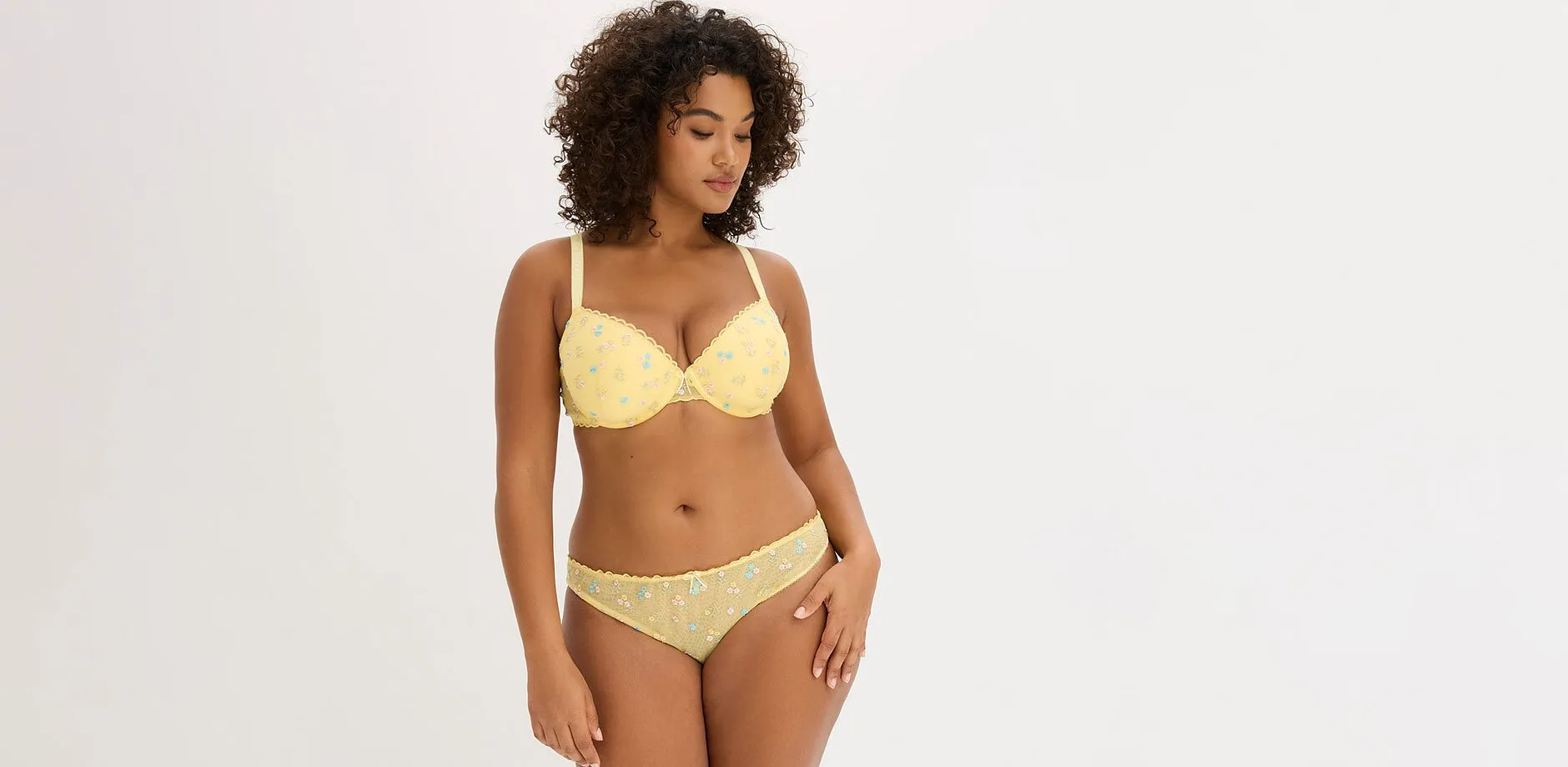 Femme v&ecirc;tue d'une lingerie jaune &agrave; broderie florale.