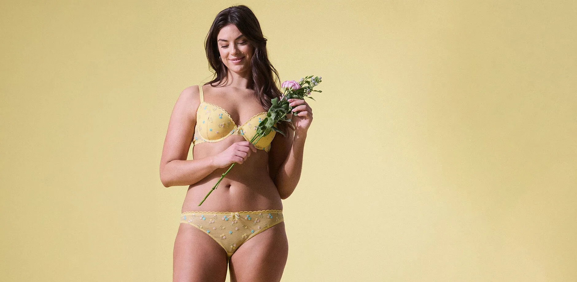 Femme v&ecirc;tue d'une lingerie de couleur jaune &agrave; broderie florale. 