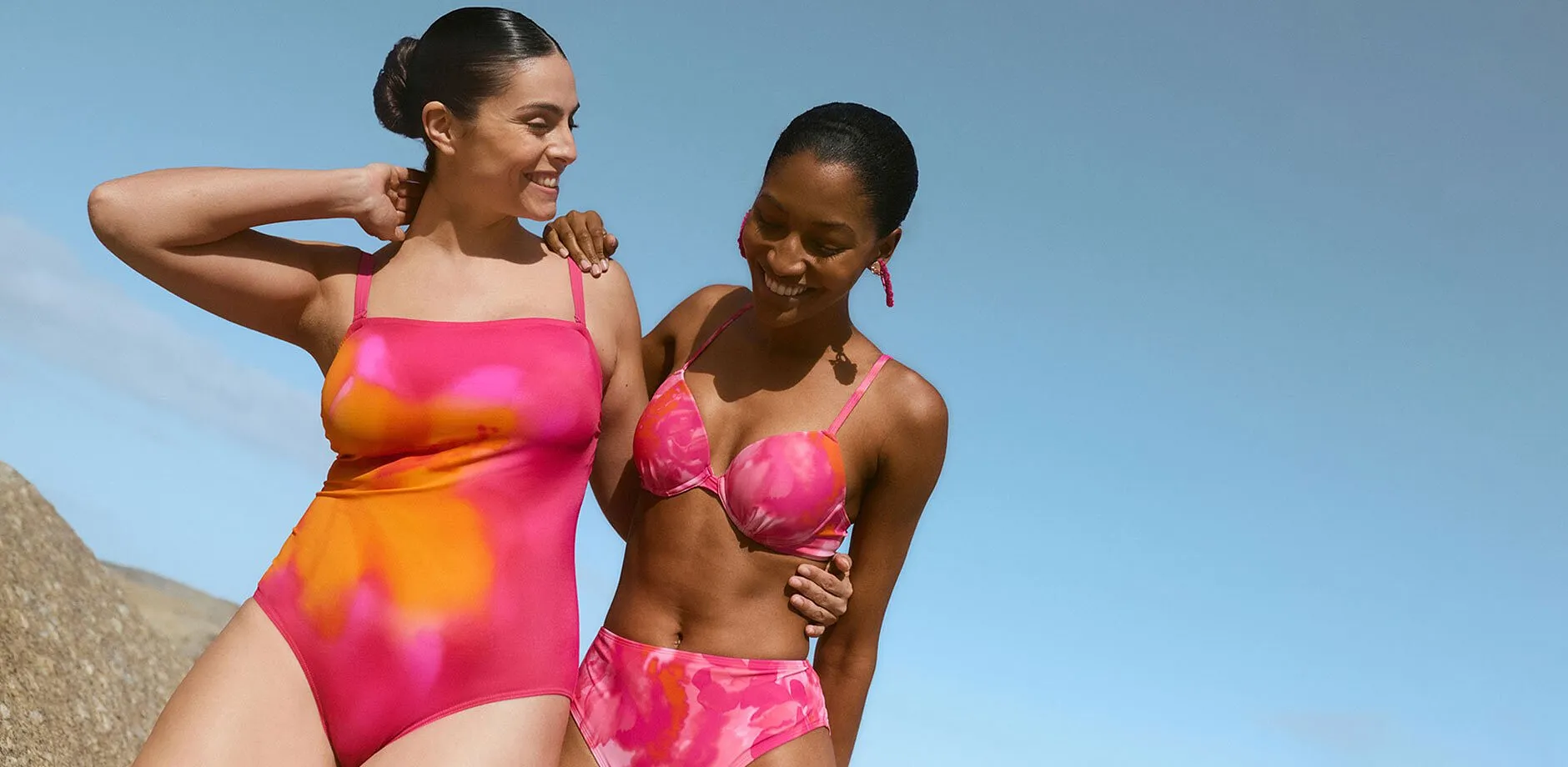 Deux femmes en maillots de bain 1 pi&egrave;ce et bikini rose &eacute;clatant &agrave; la plage.