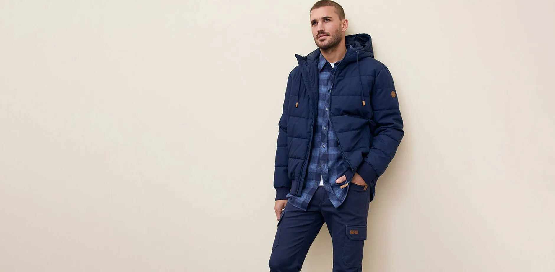 Marineblaue  Steppjacke, Jeans und blauem Karo-Hemd.