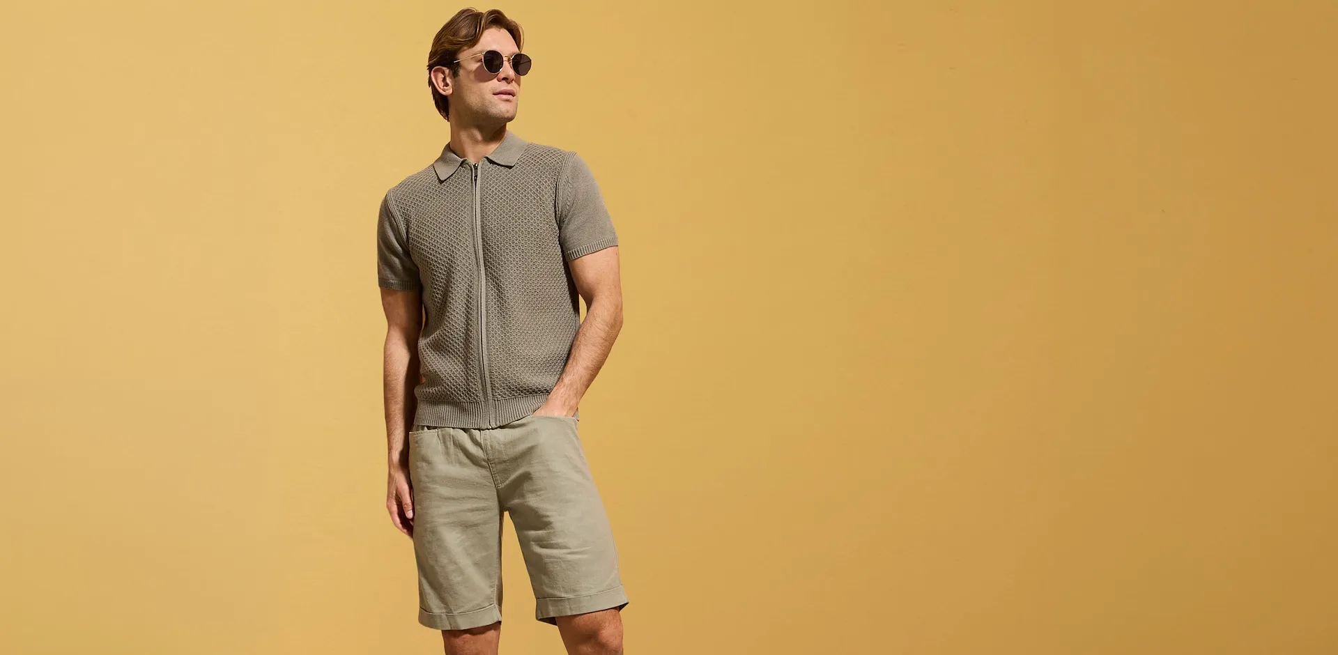 Polo gris en maille avec fermeture zipp&eacute;e et short beige pour un look estival d&eacute;contract&eacute;.