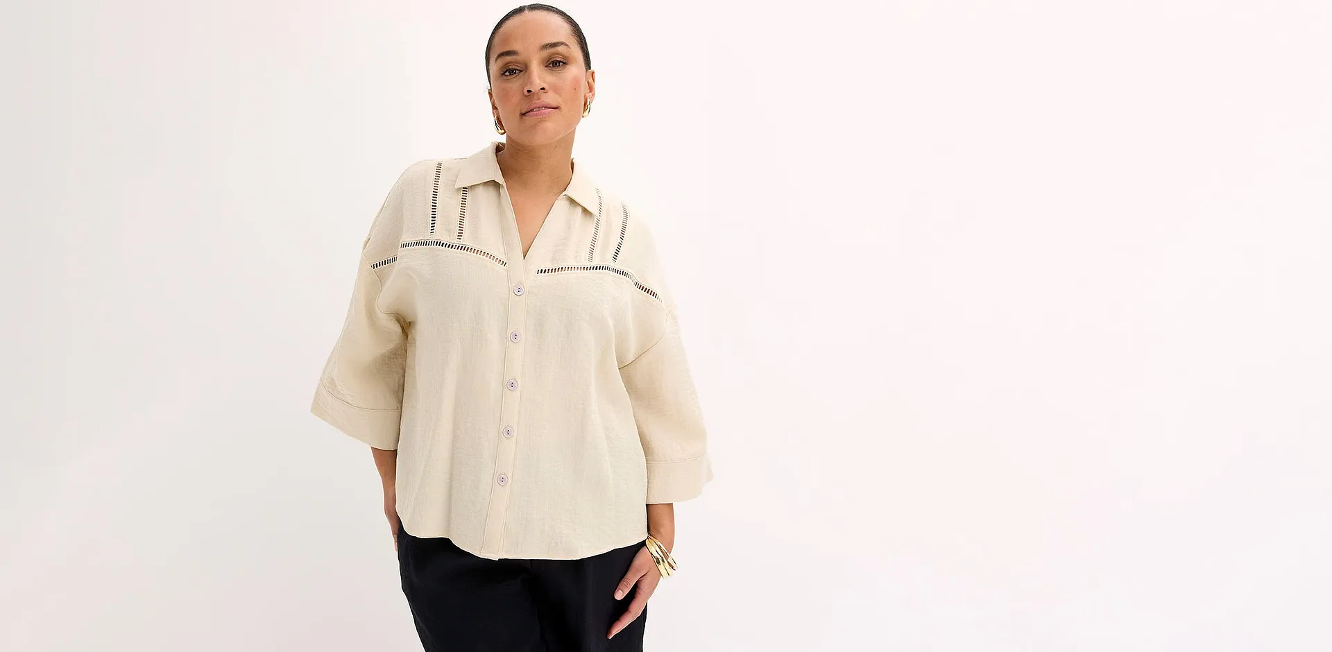 Chemisier de couleur cr&egrave;me &agrave; col classique, associ&eacute; &agrave; un pantalon noir.