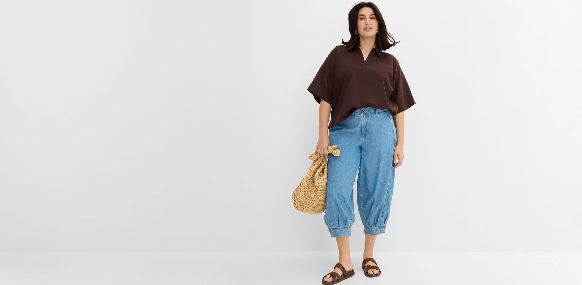 Tenue compos&eacute;e d'une blouse marron et d'un jean large avec sandales et sac en paille. 