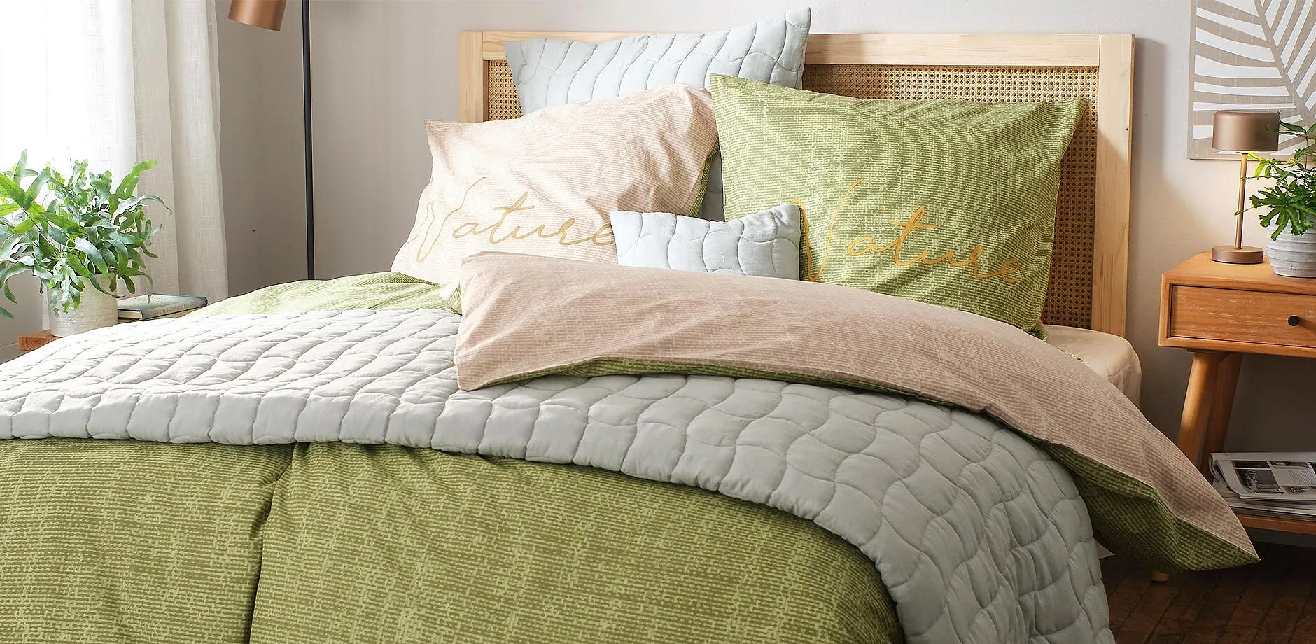 Parure de lit dans des tons vert et gris avec divers coussins cr&eacute;ant une ambiance cosy dans la chambre &agrave; coucher.