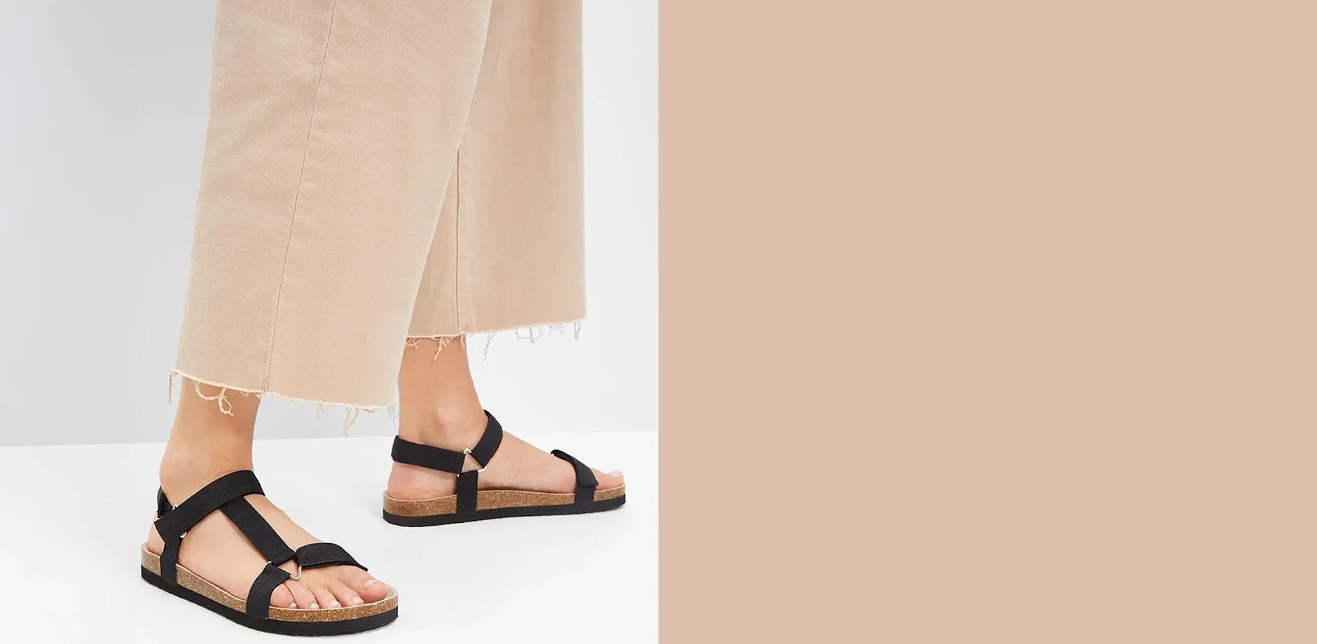Les sandales noires avec brides compl&egrave;tent parfaitement le pantalon large beige pour cr&eacute;er un long d&eacute;contract&eacute;.