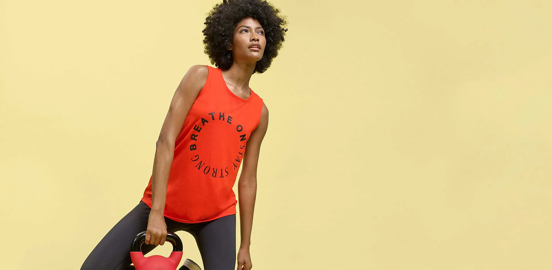 D&eacute;bardeur rouge avec inscription "Breathe On Stay Strong" et legging fonc&eacute; pour le sport.