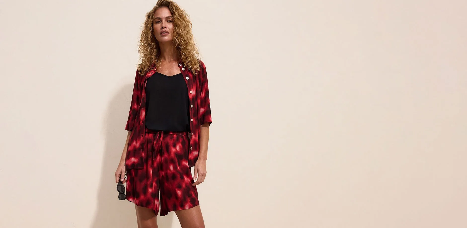Ensemble &agrave; imprim&eacute; batik rouge et noir avec chemise ouverte, short et top noir.