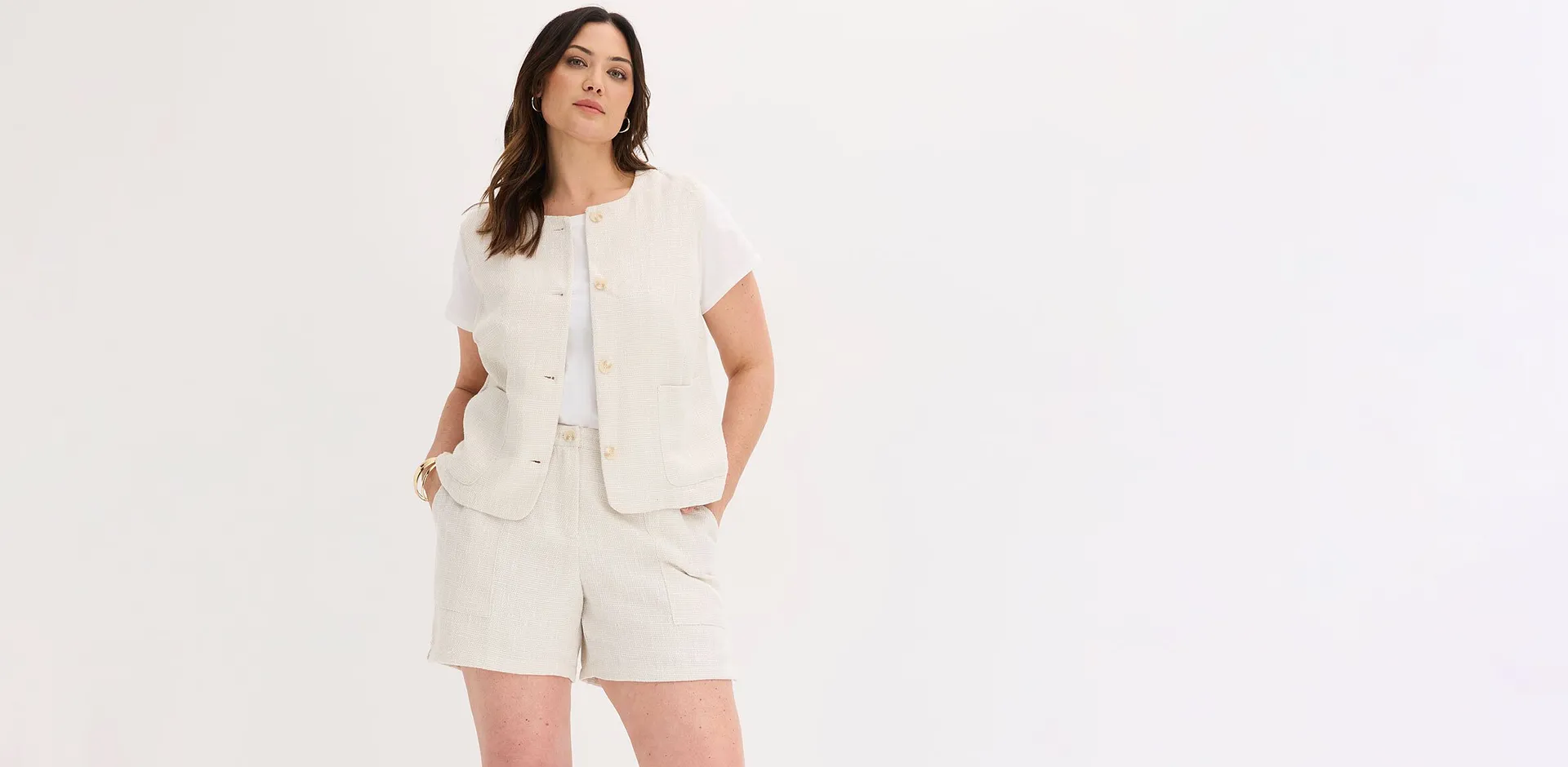 Ensemble deux pi&egrave;ces chic en couleur claire avec short et veste sans manches fa&ccedil;on tweed.