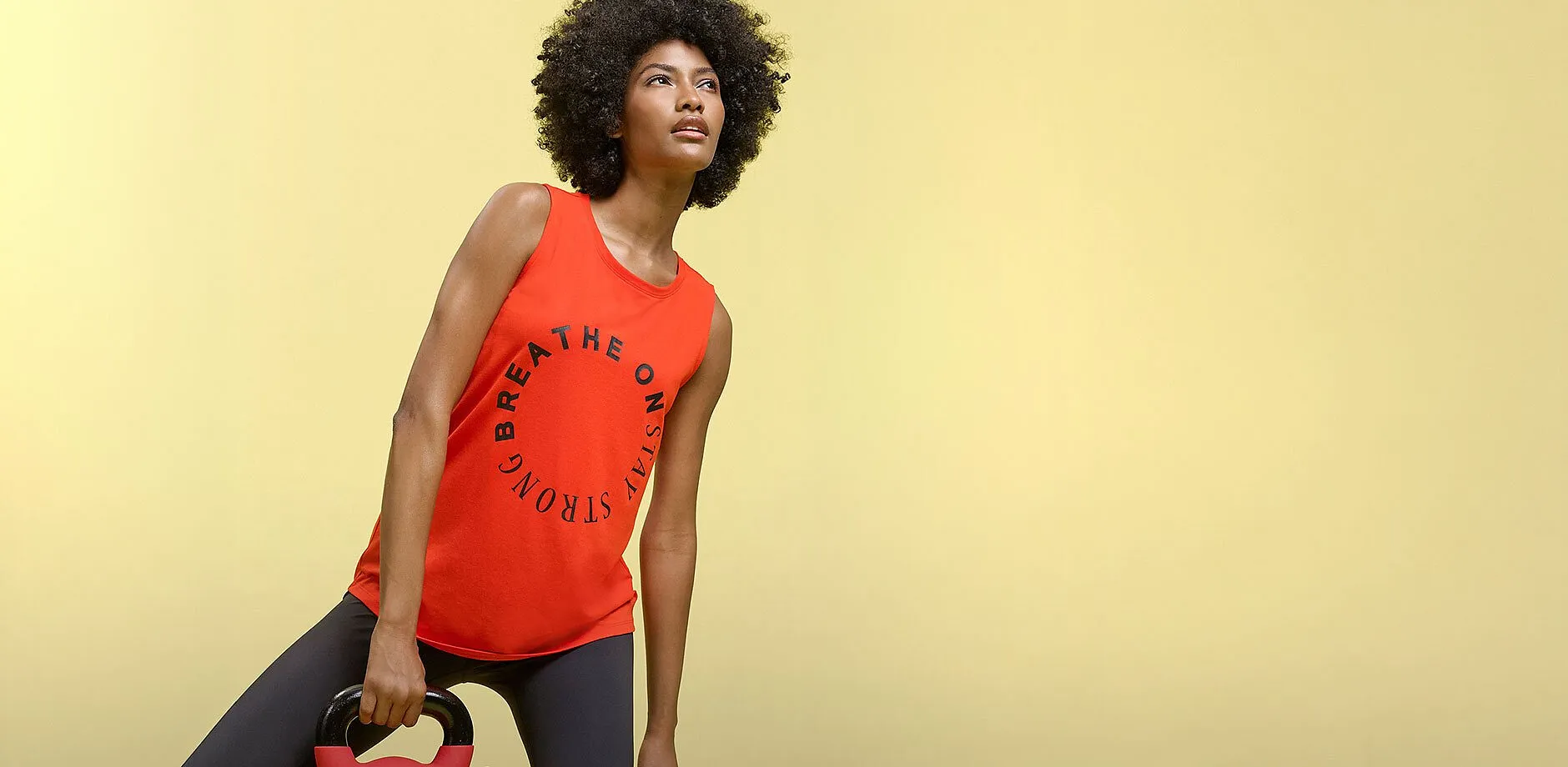 Haut rouge sans manches avec inscription et legging de sport fonc&eacute; pour vos s&eacute;ances d'entra&icirc;nement.