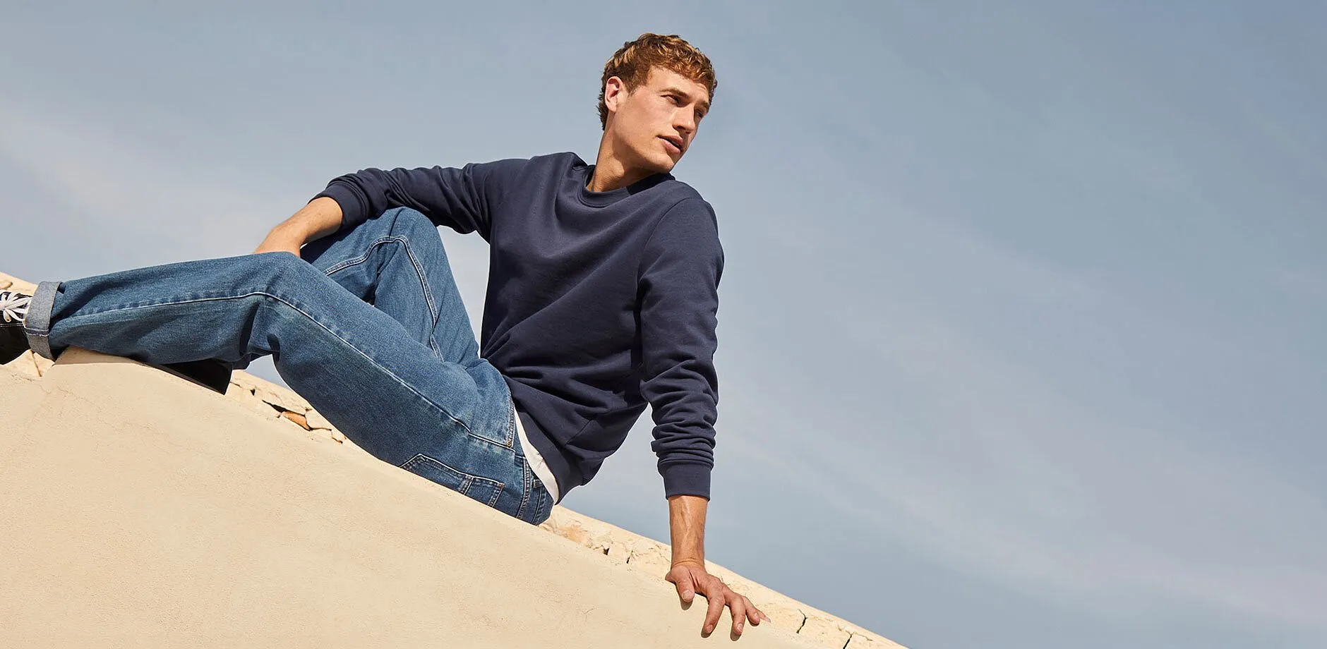 Schlichtes blaues Sweatshirt, klassische Jeans und Sneaker.