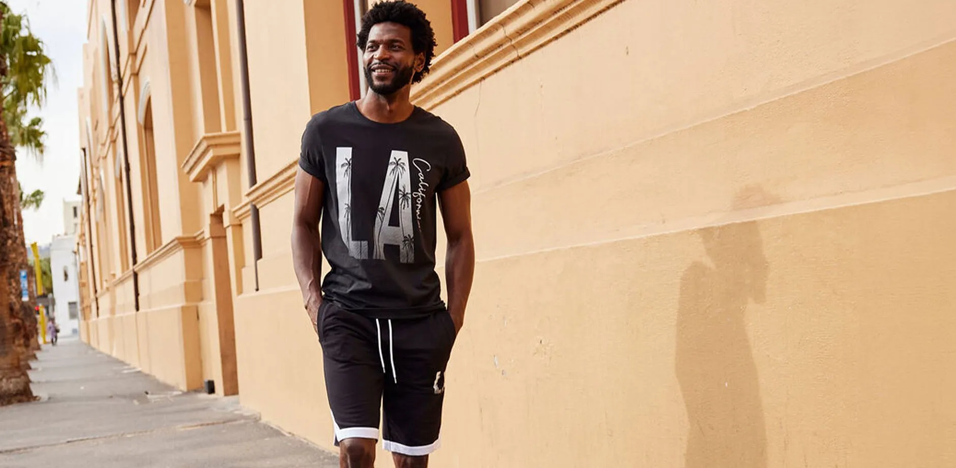 L&auml;ssig in schwarzem T-Shirt mit &bdquo;LA&ldquo;-Print und passender Jogginghose gekleidet.