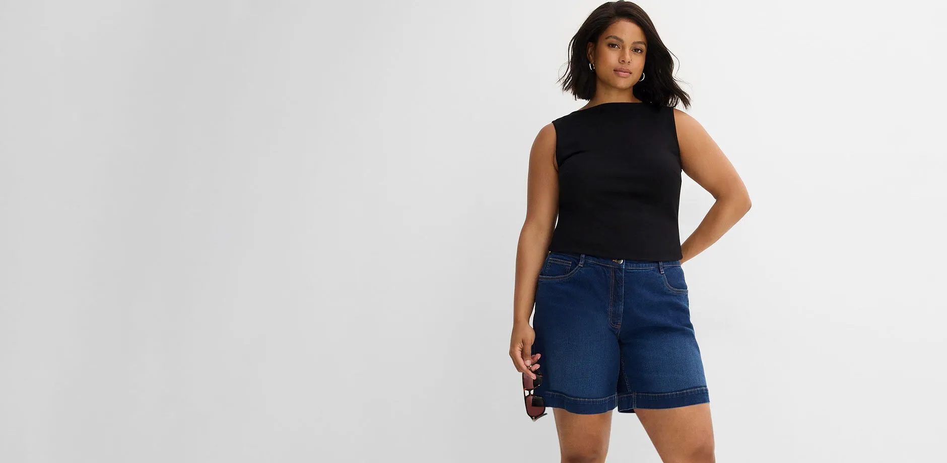 Top noir et short en jean bleu d&eacute;contract&eacute;.
